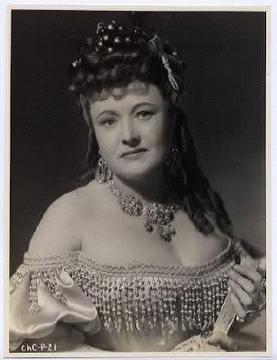 A middle-aged lady in an ostentatious dress, with plentiful decolletage on show.